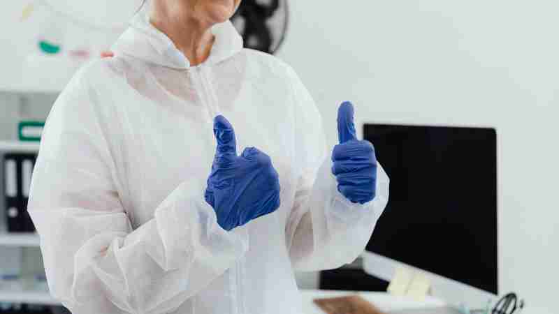 Healthcare worker in a protective suit and gloves giving a thumbs up in a laboratory setting., tags: und - pexel